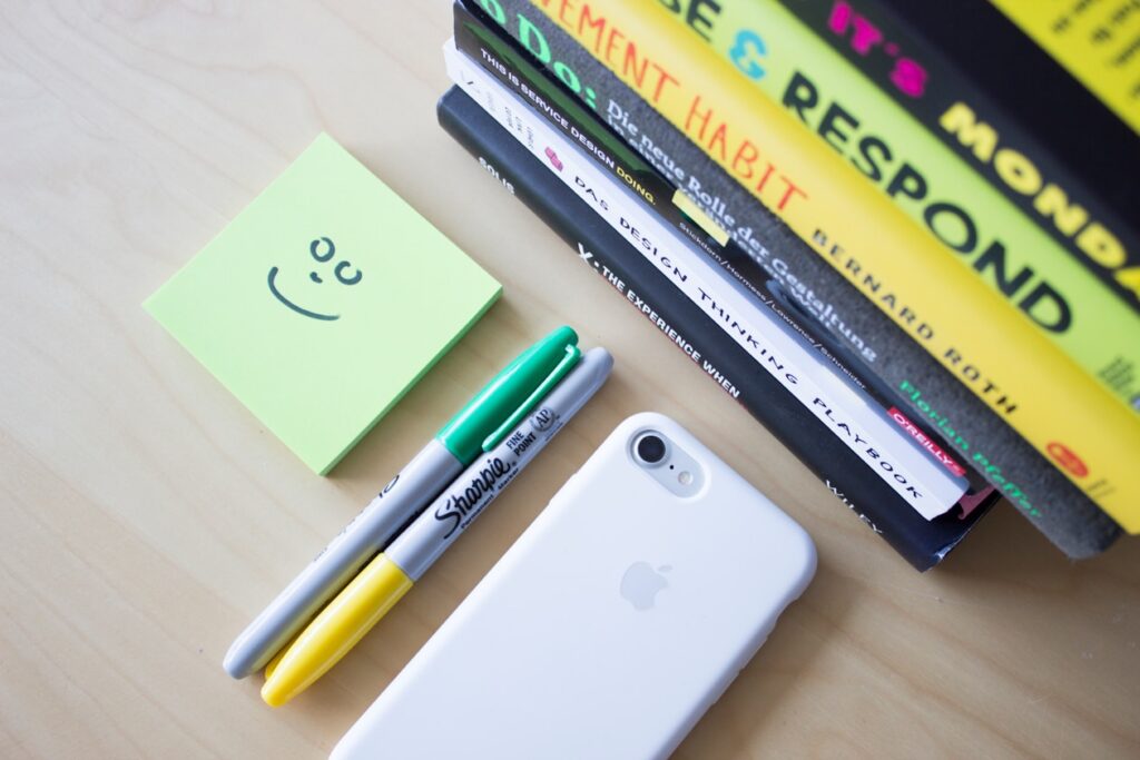two Sharpie markers beside iPhone and sticky notes